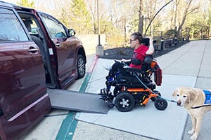Handicap Person in Wheelchair loading into handicap accessible van with dog